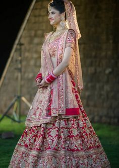 a woman in a red and gold bridal gown posing for the camera with her hand on her hip