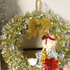 a christmas wreath with a teddy bear hanging from it's side and other decorations around it