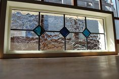 a stained glass window sitting on top of a wooden table next to a window sill