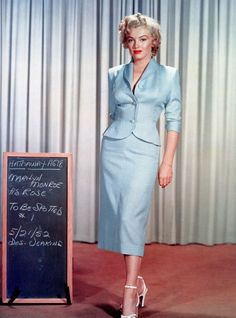 a woman standing next to a blackboard with writing on it