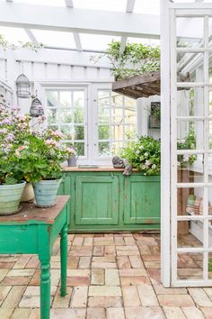 a kitchen with green cabinets and potted plants