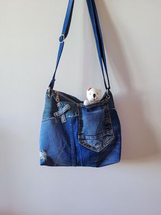 This everyday shoulder bag is made from used  jeans. The preserved details of the original pants ads a touch of relaxed elegance, perfect for effortlessly stylish outing.  It's a bag of moderate dimensions. There are exterior  pockets  - open for quick access. Inside a pocket for your phone makes it easy to find your belongings. The bag has detailed leather decorations, giving it an elegant and sophisticated look. Equipped with an adjustable shoulder strap that extends to the perfect length, thi Unique Jeans, Denim Purse, Leather Decor, Purses And Handbags, Shoulder Strap, Art Collection, Shoulder Bag, Bathing Beauties, Accessory Gift