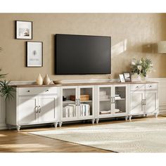 a living room with a large tv on top of a white entertainment center next to a rug