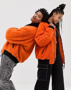 two people standing next to each other wearing orange jackets