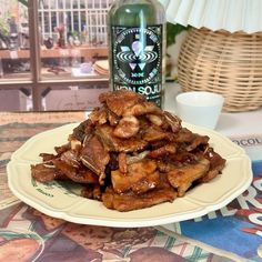 a white plate topped with meat next to a bottle