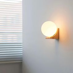 a wall light mounted on the side of a white wall next to a window with blinds