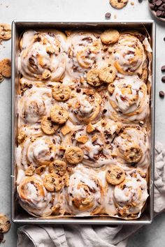 a pan filled with cookies and frosting on top of a white table next to chocolate chips