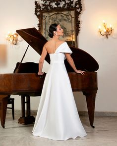 a woman in a white dress standing next to a grand piano and looking up at the sky