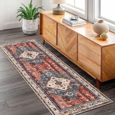 a large rug is on the floor next to a wooden dresser and window sill