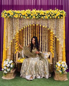 a woman sitting in front of a flower decorated stage