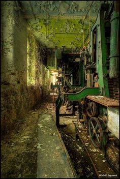 an old abandoned factory with machinery and moss growing on the walls, along with rusted flooring