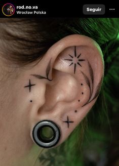 an ear tattoo with crosses and stars on it