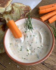 a bowl of ranch dip with carrots and pita bread on the side next to it