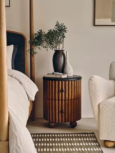 a bed room with a chair and a plant on top of a table in front of a mirror