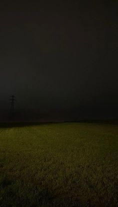 an empty field at night with power lines in the distance