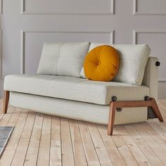 a white couch sitting on top of a hard wood floor next to a rug and wall