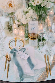 the table is set with silverware and white flowers