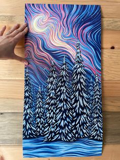 a person holding up a piece of art that looks like trees in the night sky