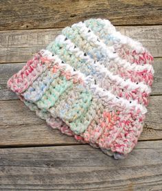 a crocheted hat sitting on top of a wooden table next to a piece of wood