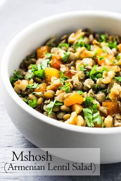 a close up of a bowl of food on a table with the words mshosh armenin lentil salad