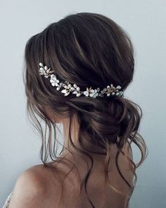 a woman wearing a bridal headpiece with flowers on it's side and long hair in the back