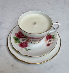 a tea cup and saucer with a candle on it sitting on a marble table