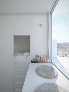 two round cushions sit on the counter in front of a window with a ladder leading up to it