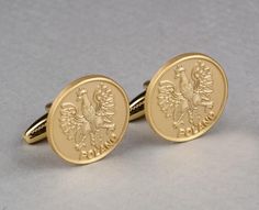 Pair of satin gold plated cuff links featuring the Polish Eagle with the word "POLAND" written beneath; for use as a fastener with link cuffs. Image measures: 0.75" in Diameter Cuff link measures: 1.0" Long Packaged in a clear hard plastic box. This design is also available as Gold Plated (Foggy), Antique Bronze Plated, and Antique Silver Plated Cuff Links! Gold Cuff Links, Polish Eagle, Gold Cufflinks, Cuff Links, Hard Plastic, Antique Bronze, Antique Silver, Poland, Silver Plate