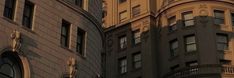 an old clock is shown on the side of a tall building in new york city