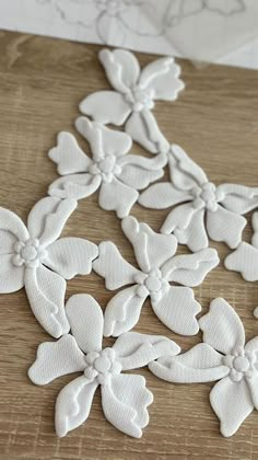 some white flowers sitting on top of a wooden table next to a piece of paper