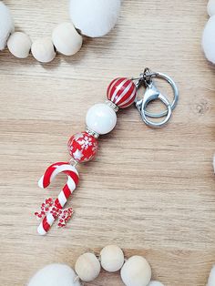 a red and white striped candy cane keychain on a wooden table with balls