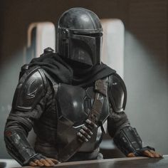 a man in a star wars costume is sitting at a table with his hand on the edge