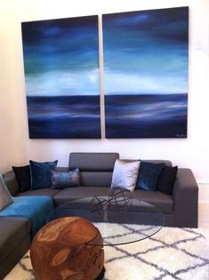 a living room filled with furniture and two paintings on the wall above it's coffee table