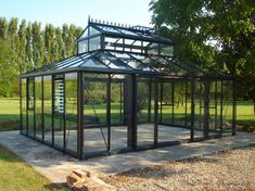 a glass house sitting on top of a cement slab in the middle of a park