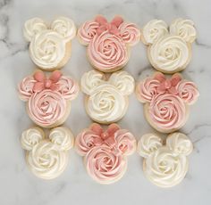 cupcakes with pink and white frosting shaped like mickey mouse heads on a marble surface