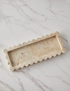 a white tray with scalloped edges on a marble surface