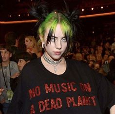 a woman with green hair and piercings standing in front of a crowd at a concert