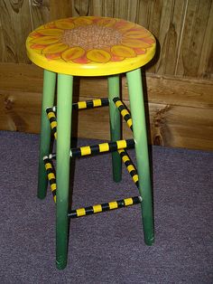 a yellow and green stool with flower painted on it