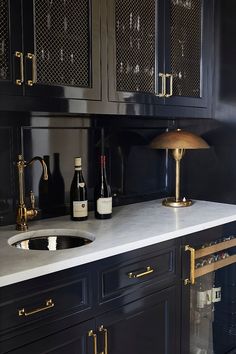 a kitchen with black cabinets and white counter tops, gold pulls on the door handles