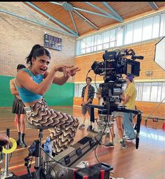 a young woman is filming while others watch from the sidelines in an indoor gym