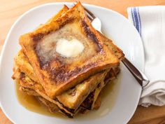 a white plate topped with french toast covered in butter and syrup next to a fork