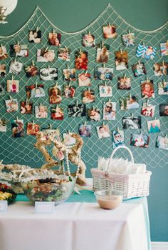 a table with pictures on the wall and a basket full of flowers next to it