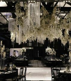 an elegant wedding setup with chandeliers and flowers hanging from the ceiling in black and white