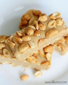 two pieces of peanut butter fudge bars on a white plate with cashews