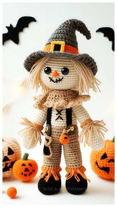 a crocheted scarecrow is standing in front of some pumpkins and bats