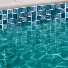 an empty swimming pool with blue tiles on the wall and water reflecting off it's surface