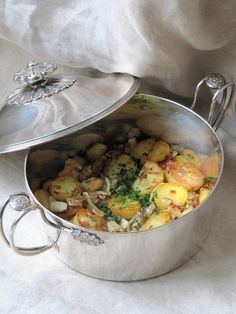 a silver pot filled with food on top of a white cloth