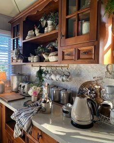 the kitchen counter is covered with pots, pans and tea kettles on it