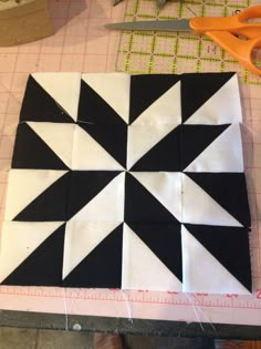 a black and white tile pattern sitting on top of a table next to some scissors