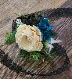 a bridal corsage with flowers and feathers on a wooden table, ready to be used as a garter